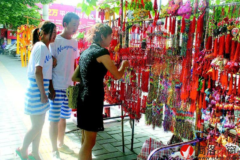 文化广场香包摊前造型各异、做工精美的香包吸引年轻人购买。