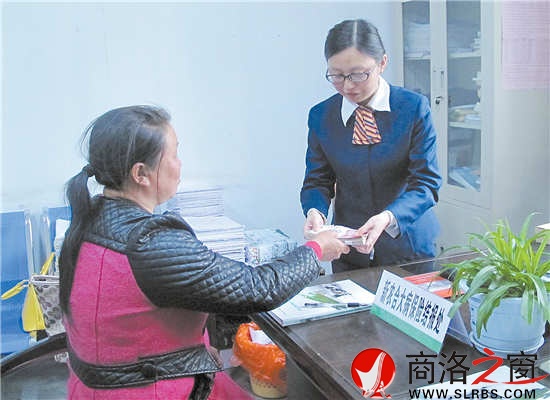 4月23日,谢自芳从工作人员手中接过大病保险报销资金。