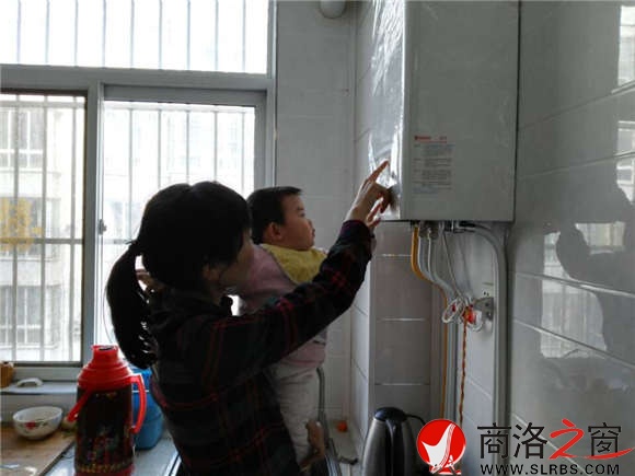 家住市区香菊小区的李女士正在操作自家刚刚安装的燃气壁挂炉，提升室内的温度。