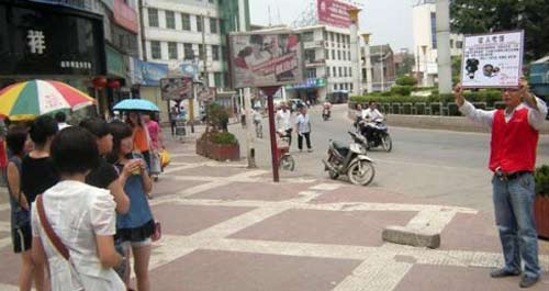 小伙街头宣传乙肝科普知识 高举身份牌征人吃饭