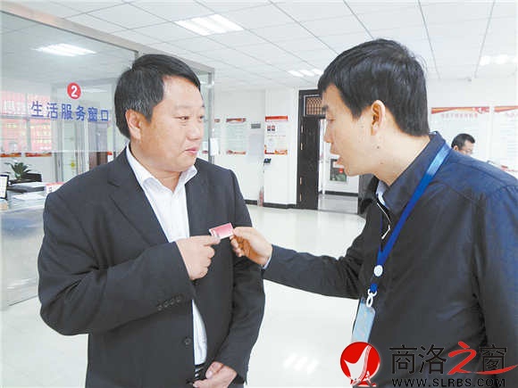 在镇安县新城社区便民服务大厅里,参会人员对社区工作人员挂牌上岗很感兴趣。(记者 柯岩 摄)