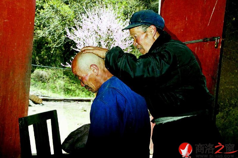 74岁的邓自强在屋门口给71岁的弟弟邓自贵剃头。