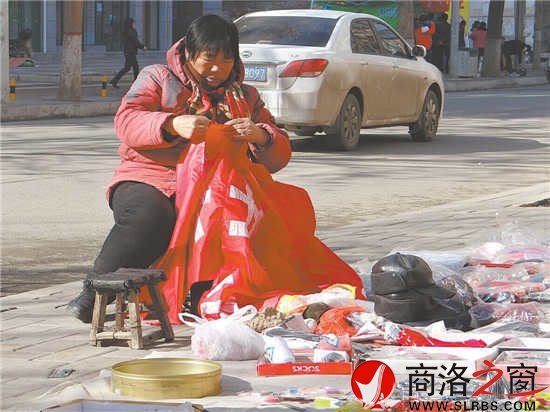 趁着阳光正好，摆地摊的老人不忘做做手工活。