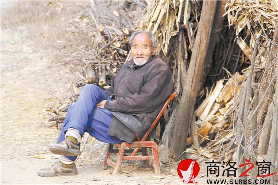 花白胡子的赵恩老人靠着柴垛悠闲地听着秦腔戏