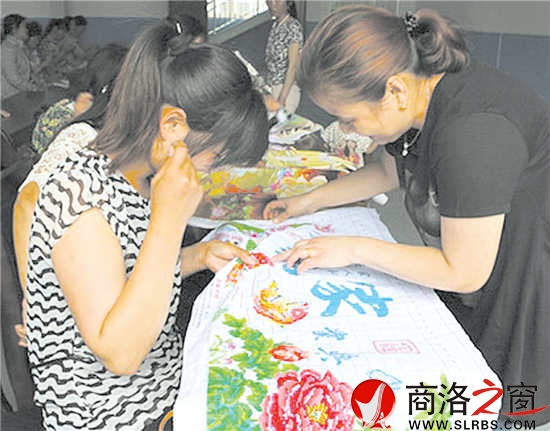 搬迁户周玲正一针一线地绣牡丹图
