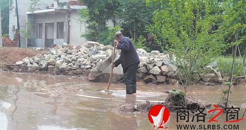 20日上午，杨三如正在清理门前的淤泥。
