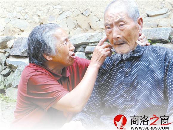 周秀芹细心地给张新文戴上助听器。自从张新文老人失聪后，老伴就是他的耳朵。