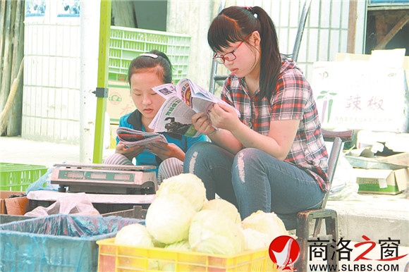 商州区杨斜镇集市上，南思佳和妹妹在帮父母卖菜，闲暇之余，她们会拿起课外读物翻一翻。在这个假期里，她们呆的最多的地方就是这个菜摊。